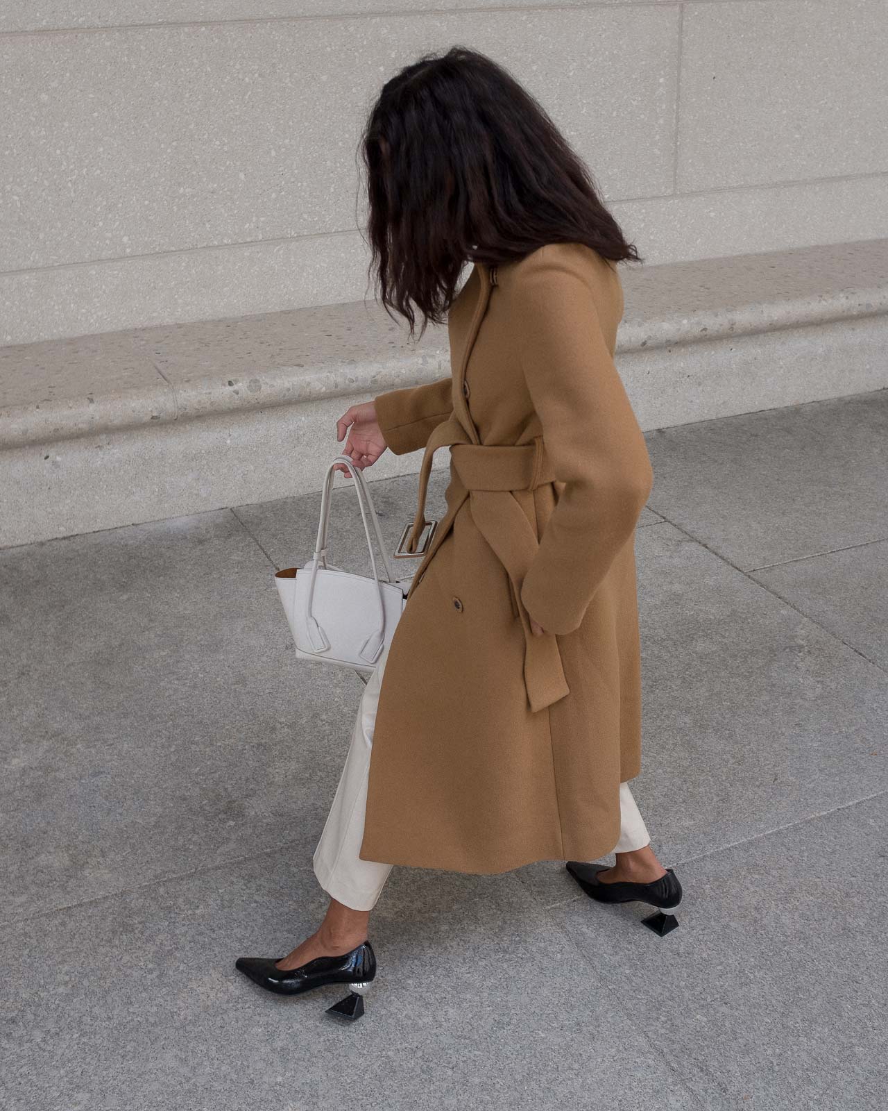 storm wears black mules from yuul yie combined with by malene birger camel coat and white arco bottega veneta bag