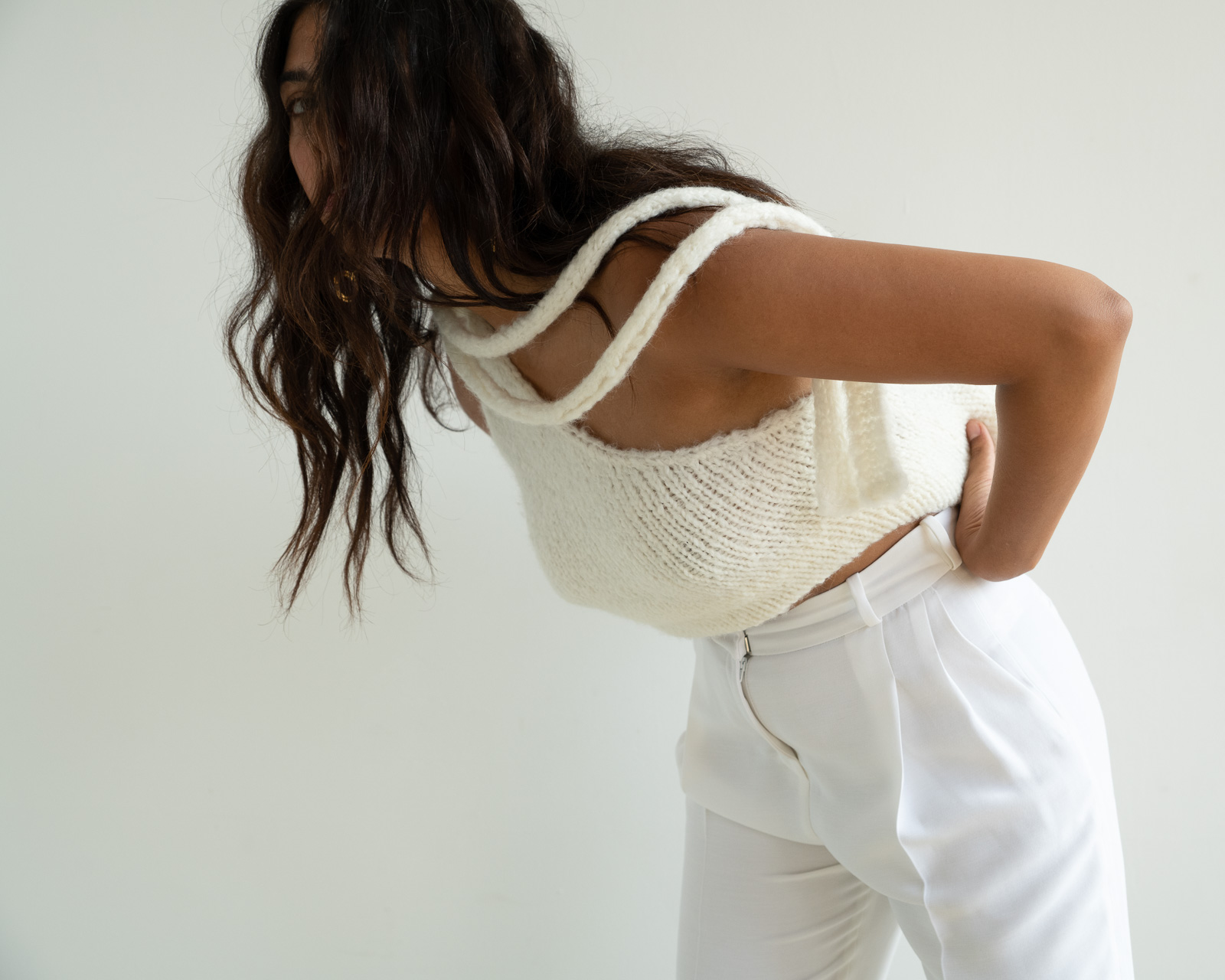 Storm wes wears malaika Raiss white knit top with gold earrings and white pants